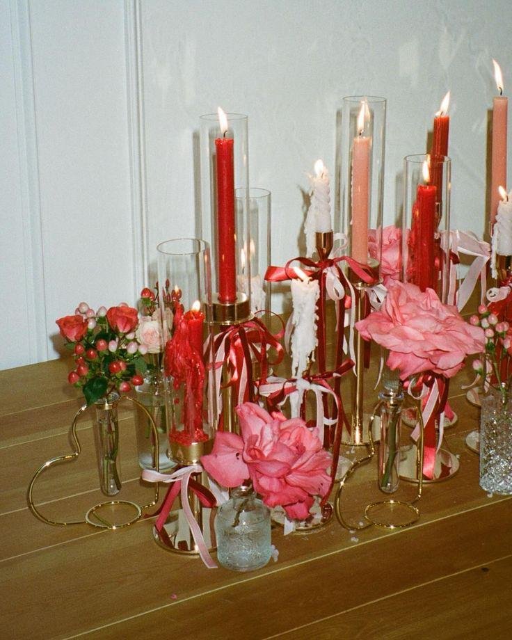 A setup for an event with pink and red candles and roses, as well as other flowers